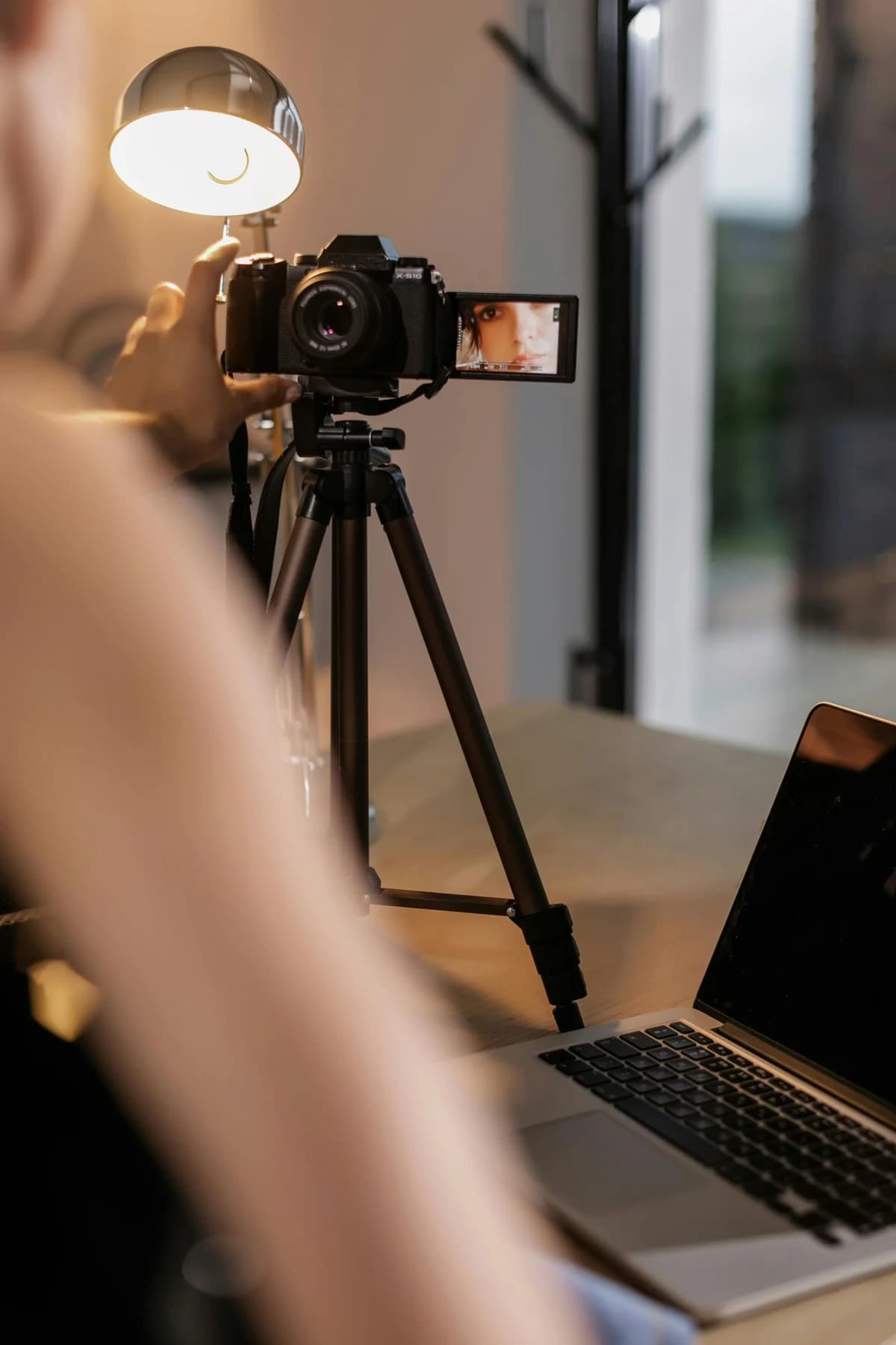 Camera on a tripod beside a laptop on a desk: a videographer's setup where DCAST Mini Uploader sends the render to the client