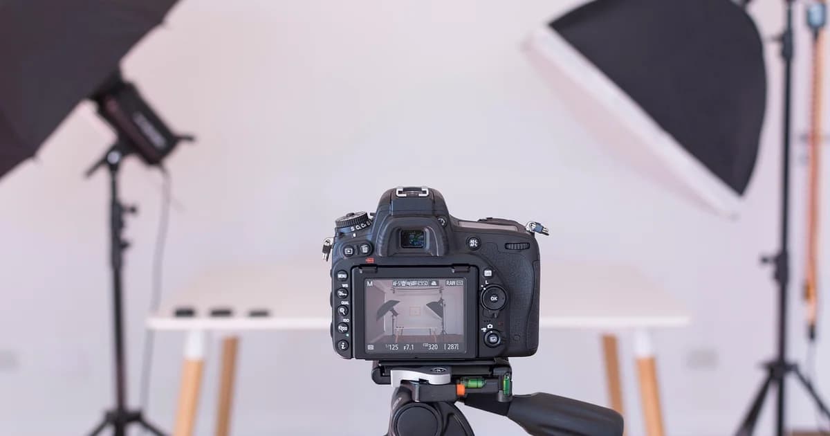 Camera on a tripod in a studio with softbox lights and a plain backdrop