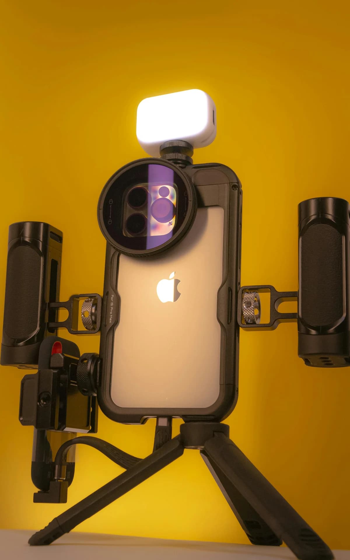 A smartphone mounted in a video rig with side handles, ready to stream a backup feed with Larix